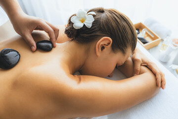 Hot stone massage at spa salon in luxury resort with day light serenity ambient, blissful woman...
