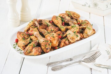 Prepared chicken pieces, including drumsticks and wings, are seasoned and arranged on an oval...
