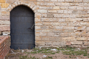 old metal door with lock,  an ancient arched door in a fortress wall, a door reinforced with steel...