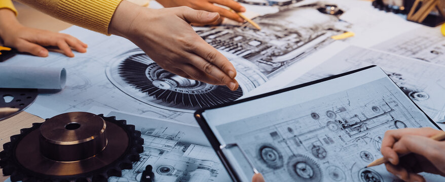 A dynamic scene of a diverse design team engaged in hands-on collaboration over technical blueprints, focusing on innovative machinery and engineering solutions. SACTR