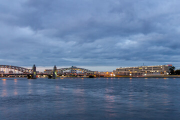 Naklejka premium Dusk view of illuminated Bolsheokhtinsky Bridge over Neva River with city lights reflection in water. Saint Petersburg, Russia.