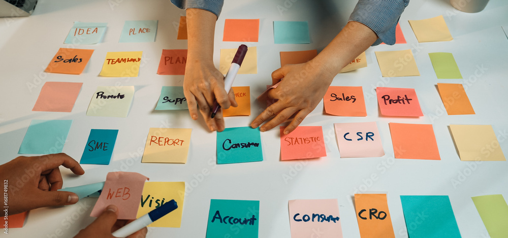 Aufkleber hands writing on colorful sticky notes during a collaborative brainstorming session in an office. th
