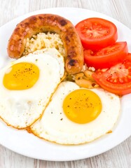 Fried eggs, sausage, rice, beans, and tomatoes
