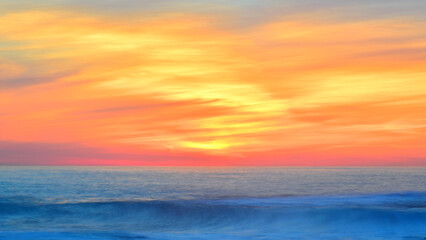 Golden sunset enhancing the movement of clouds and waves.