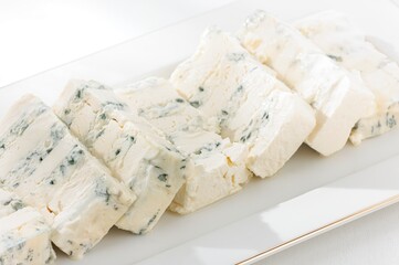 Delicious wedges of Gorgonzola cheese are arranged on a pristine white plate, presenting a...