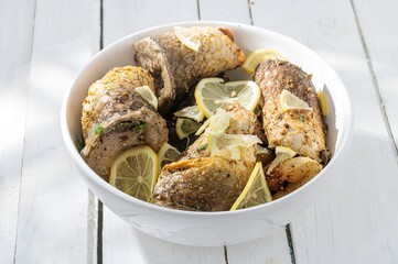 The succulent white fish is baked until golden and tender, adorned with bright yellow lemon slices....