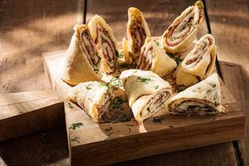 Several appetizing pastry rolls with savory filling are meticulously arranged on a rustic wooden...