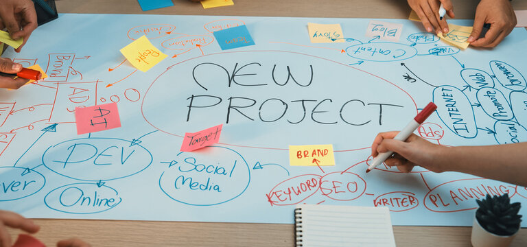 A vibrant workspace showcasing a collaborative brainstorming session with hands writing on a large paper. Colorful sticky notes highlight various ideas for a new project. SACTR
