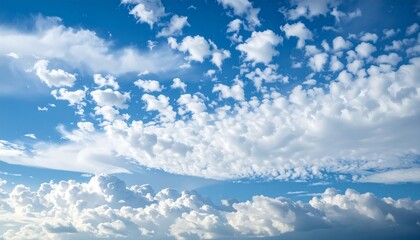 A vast expanse of a vibrant blue sky dotted with soft, fluffy white clouds, showcasing a beautiful interplay of light and shadow.