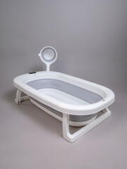 Baby bathtub with grey stripe and ladle on grey background