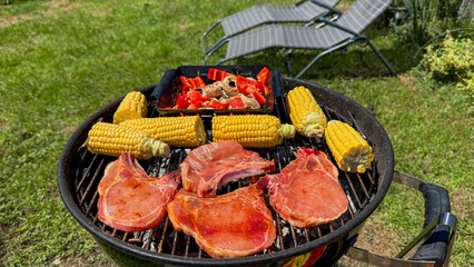 Grilled corn and succulent pork chops sizzle at a summer solstice BBQ, mouthwatering embrace of...