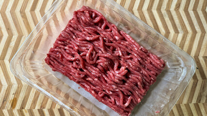 Enticing raw mince nestles in clear packaging like tangled yarn, symbolizing culinary alchemy and...