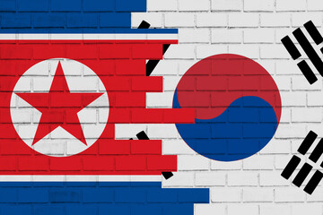 colourful painted big national flag of south korea and flag of north korea on a massive old brick wall background.