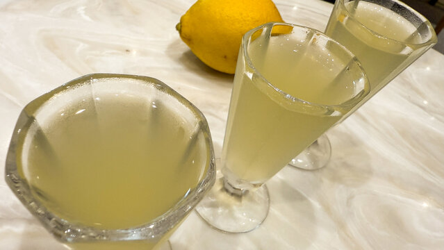 Limoncello glasses shimmer beside a sunlit lemon, echoing Amalfi Coast zest, ideal for Italian Festa della Repubblica