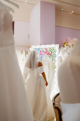 Bride standing in front of mirror trying on dress in atelier