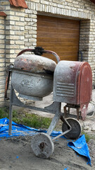 Rustic cement mixer exudes industrial charm as it stands sentinel-like against the brickwork, ideal...
