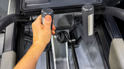 Hand grips elliptical with determination, fitness journey ignites, European male hand, National Physical Fitness and Sports Month celebration