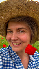 Smiling Caucasian woman in gingham and straw hat amidst poppies, evoking summer solstice bliss and...