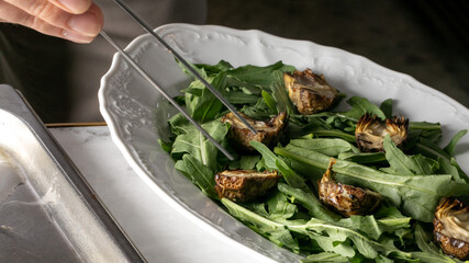 Aromatic chargrilled artichokes nestle amid vibrant arugula, an ode to Mediterranean harvest...