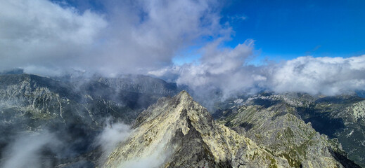 Dramatic mountain ridge rising above the clouds in the Tatra Mountains under a bright blue sky.