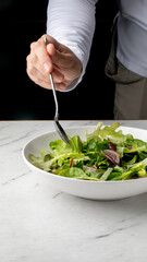 A hand poised above a vibrant salad whispers tales of Veganuary choices, Green Monday rituals, and mindful eating delights