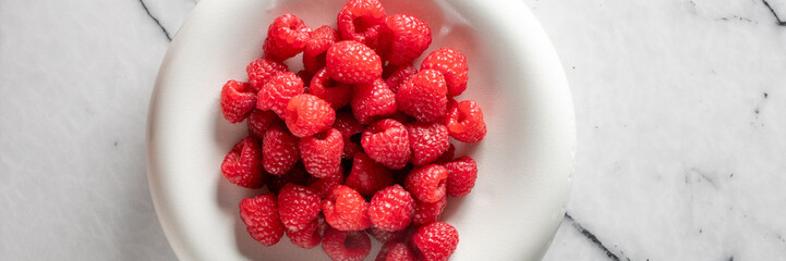 Juicy raspberries cascade in a porcelain bowl, evoking midsummer's bounty and celebrating Canadian...