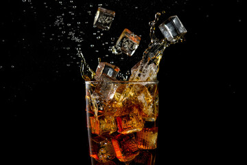 A glass of sparkling cola splash background with ice cubes