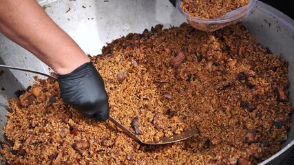 Chef serving traditional indian biryani rice with meat in large pot