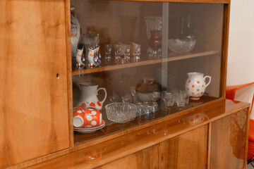 The vintage cabinet features a collection of glassware and ceramic pieces, arranged neatly behind glass doors. The warm wooden tones create an inviting atmosphere in the room