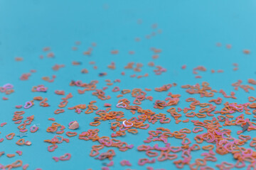 Scattered pink and orange heart-shaped confetti on a vibrant blue background, perfect for romantic...