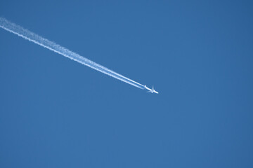 twin engined jet liner aircraft with contrails, in flight at high altitude, clear blue sky