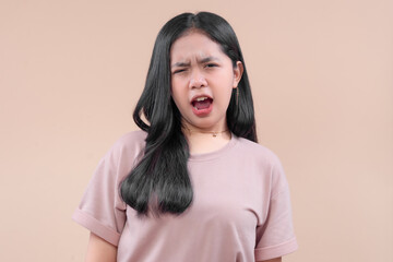 Young Asian woman in casual modern style showing a surprised and dramatic expression, wearing a pastel t-shirt while reacting emotionally against a plain neutral background.