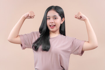 Confident Asian woman in casual modern outfit showing strong arm pose, smiling with cheerful expression, symbolizing strength, positivity, and energy.