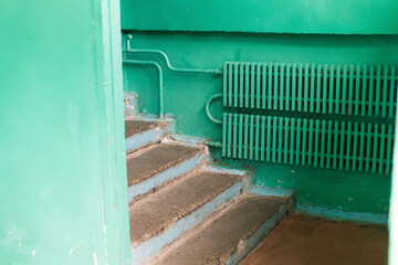 Interior of an old building in poor condition with green painted walls, cracked plaster, radiator...