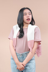 Asian woman in modern casual style, wearing pastel shirt, denim jeans, and knit sweater, looking to the side with open mouth expression, showing curiosity and youthful charm.