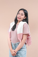 Asian woman with long black hair wearing pastel pink t-shirt, denim jeans, and knit sweater, smiling with open mouth expression, showing casual modern fashion and youthful charm.