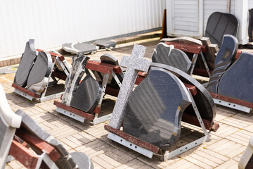 Various gravestones and memorial markers are displayed outdoors at a cemetery supply center....