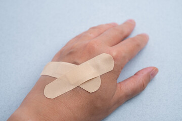 Female hand with medical adhesive plaster close-up. Adhesive plaster on damaged skin. First aid for wounds and cuts