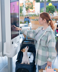 Caucasian woman makes a purchase at a self-service counter with a Jack Russell terrier dog in a...