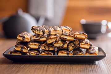 Sfogliatine glassate with chocolate. Italian crispy dessert on plate on wooden table.