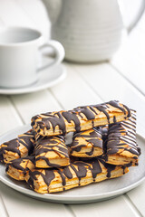 Sfogliatine glassate with chocolate. Italian crispy dessert on plate on white table.