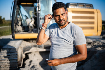 Construction worker wearing earplugs on a construction site with excavator