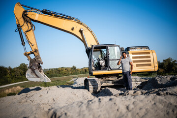 Obraz premium Construction worker using smartphone near excavator on site