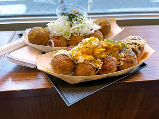 Fried octopus balls takoyaki snack with egg omelet and onion garnish. Asian street food concept. Handheld mobile photo, selective focus, non AI