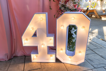 Large, illuminated 40 marquee sign lights up the foreground of an outdoor event, perfect for a 40th birthday