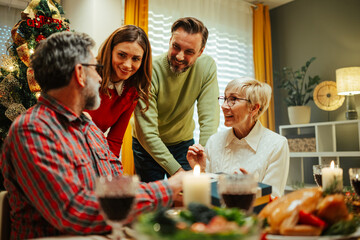 Family exchanging gifts during christmas dinner at home