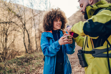 Hikers sharing hot drink during trekking in forest trail