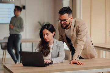 Business colleagues collaborating on laptop in modern office