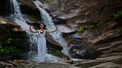 woman performing slow tai chi movements near a waterfall and river at sunset capturing harmony balance and fitness in nature