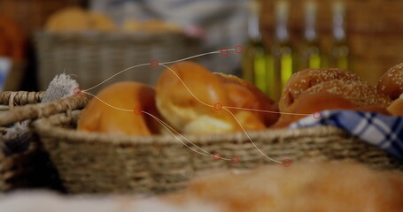 Displaying wicker baskets holding bread rolls on countertop in bakery, with oil bottles and cloth